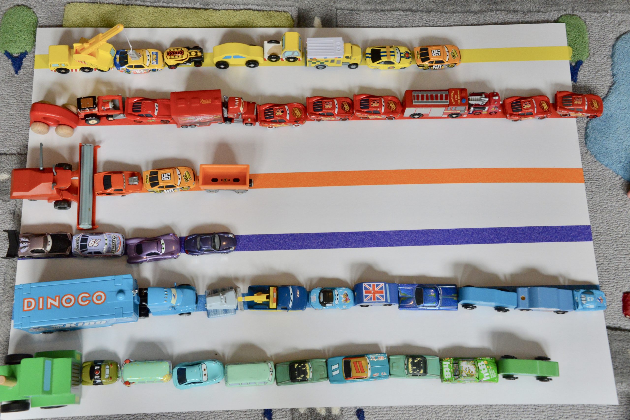 Cars lined up by colour on a sheet of cardboard