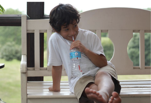 child drinking water on a bench