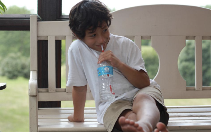 child drinking water on a bench