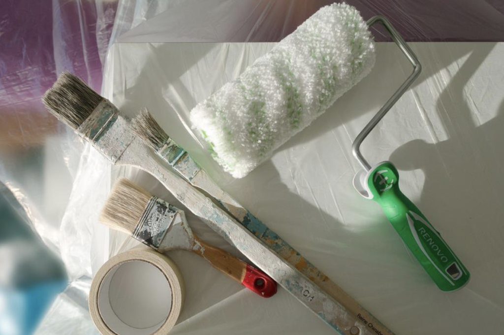 painting roller and paintbrushes on plastic sheets
