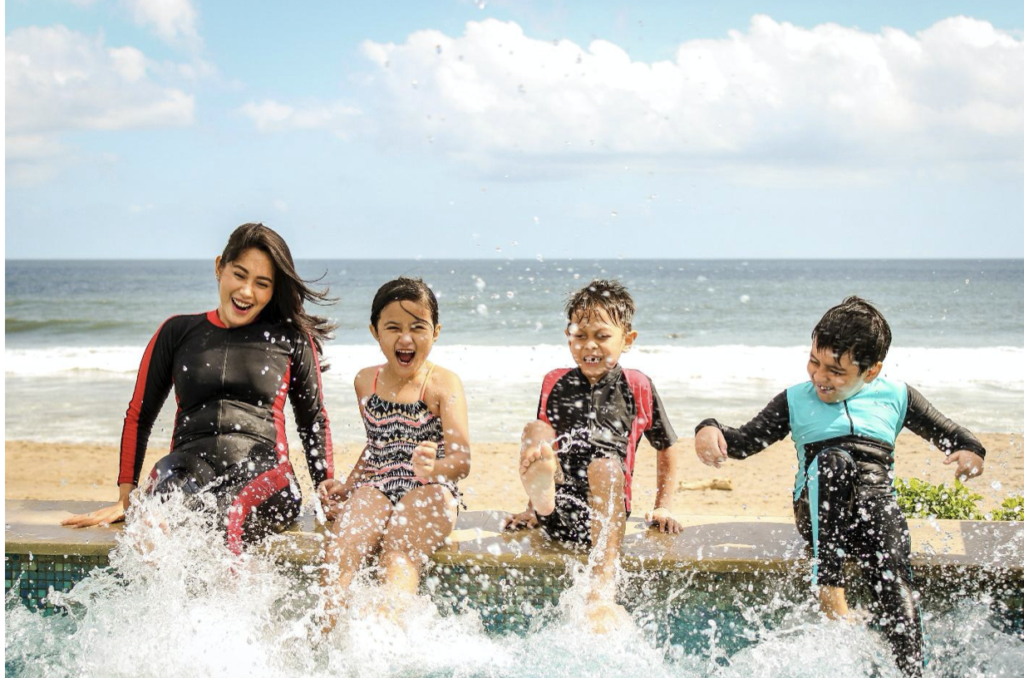 Family wearing wetsuits splashing
