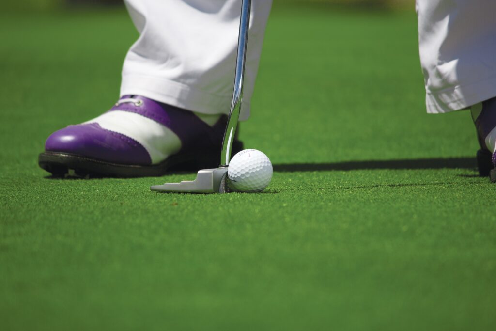 golfer with purple and white shoes and a golf ball