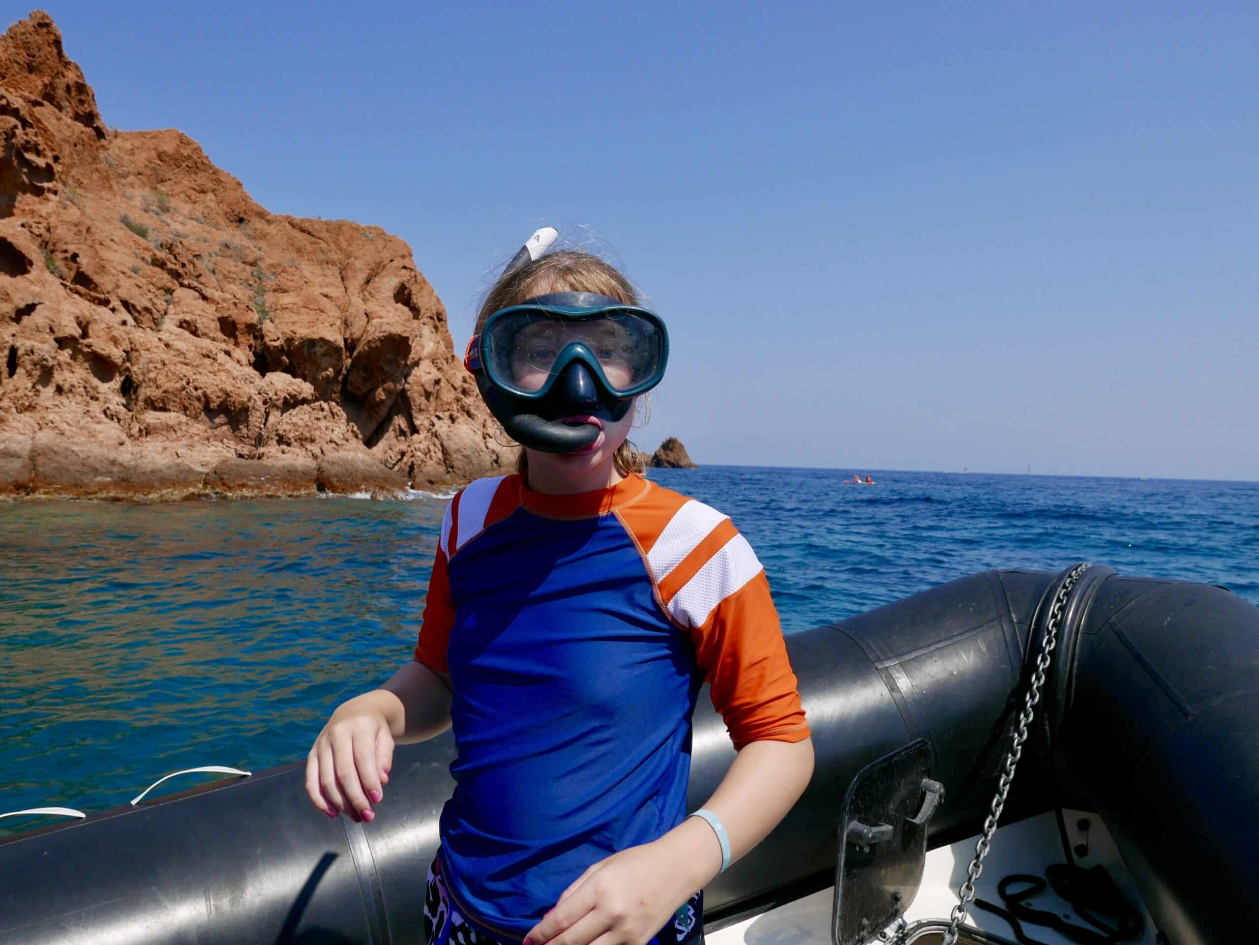 Child ready to snorkel with the Esterel coastline behind them