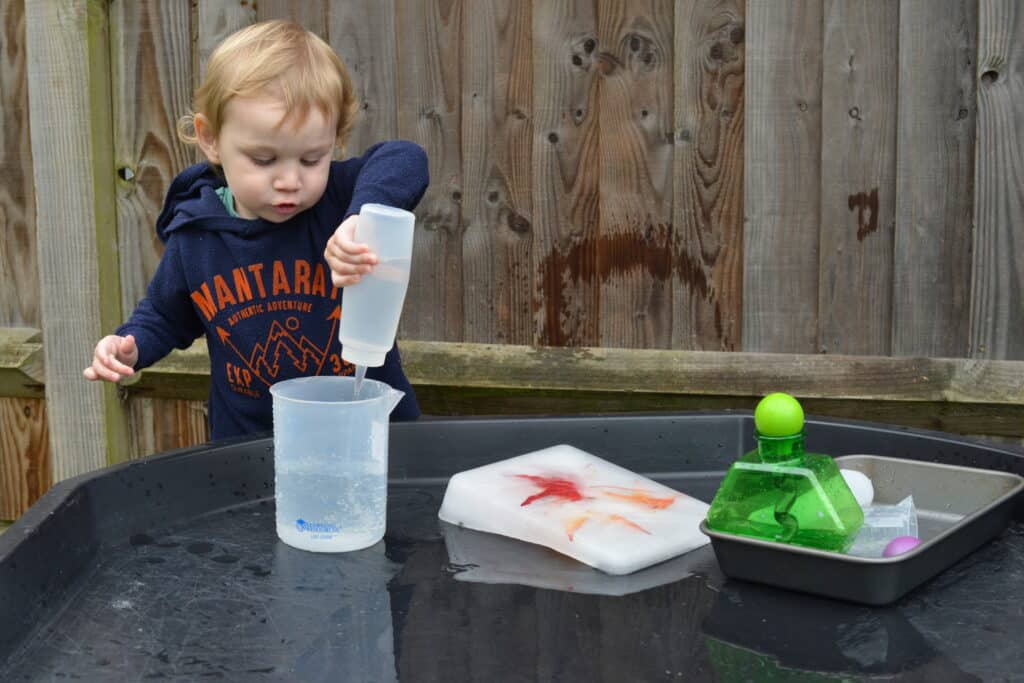 small child playing with ice and sensory toys outdoors